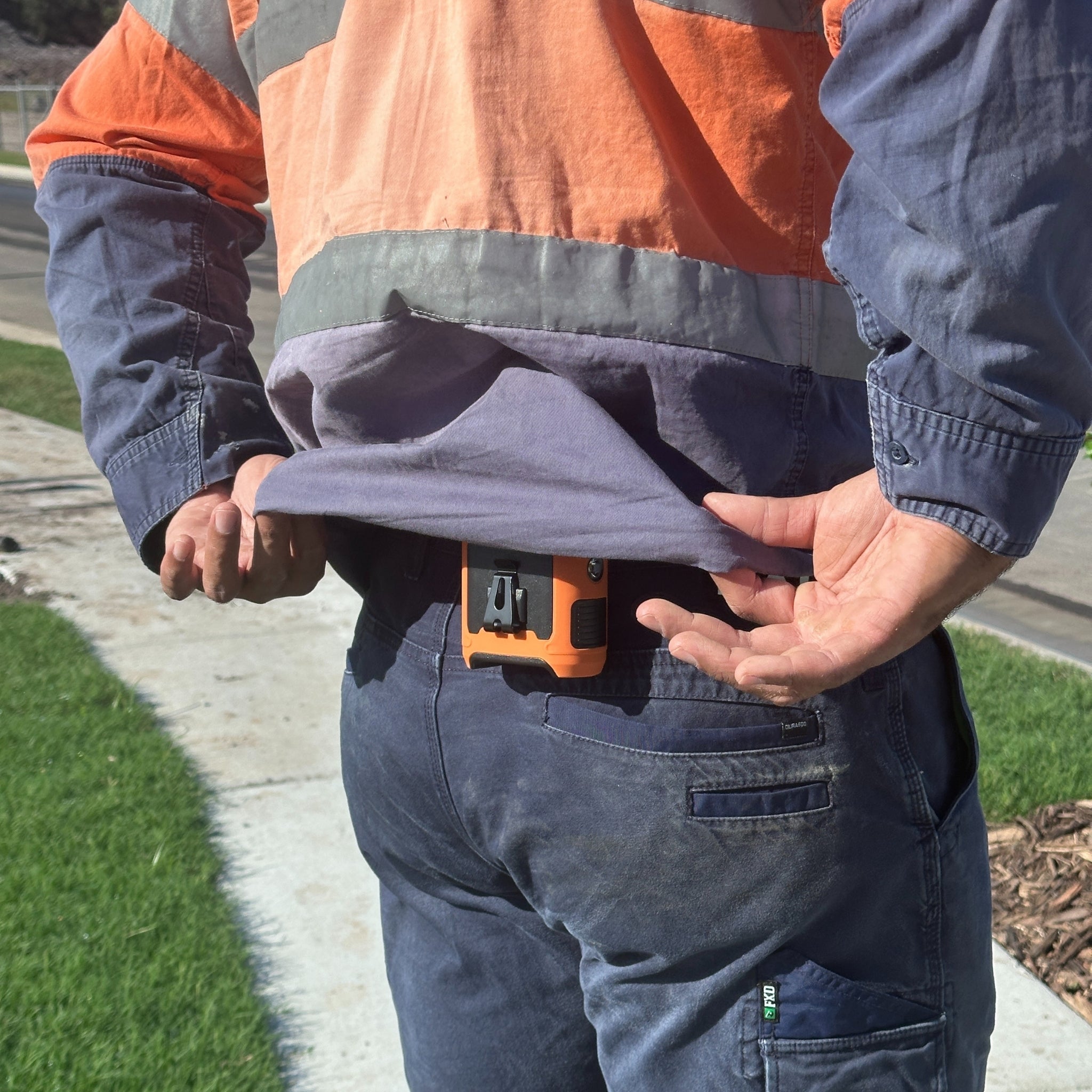 Portable waist fan clipped to tradies back onsite